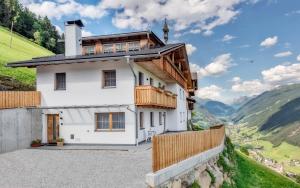 a house on a hill with a view of mountains at Ortnerhof in San Giovanni in Val Aurina