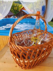a basket with glasses and a bottle on a table at Casa de la ferma Mariuca in Berbeşti