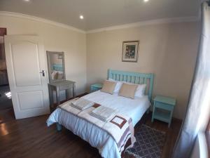 a bedroom with a bed with a blue headboard and a mirror at Studios @ Delver in Parys