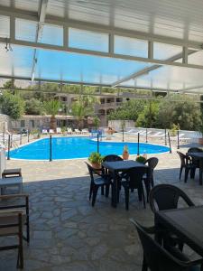 a patio with tables and chairs and a swimming pool at Voula Ilias Studios in Panormos Kalymnos