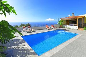 a swimming pool with chairs and the ocean in the background at Villa Ivan in Tijarafe
