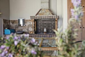 a brick fireplace in a living room with purple flowers at Romilia Guesthouse 