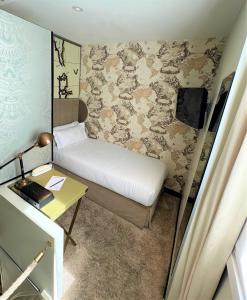 a small bedroom with a bed and a desk at Hôtel du Continent in Paris