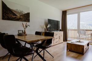 a living room with a wooden table and a television at Apart Peak Ötztal in Längenfeld