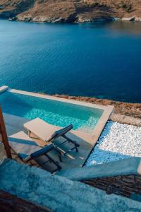 - une piscine avec 2 chaises longues et l'eau dans l'établissement Ble Kythnos Suites, à Episkopí