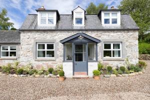 una casa de piedra con una puerta azul en una entrada de grava en Exceptional cottage with parking, en Blairgowrie