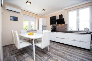 a kitchen with white cabinets and a white table and chairs at Aquamarine House in Tivat