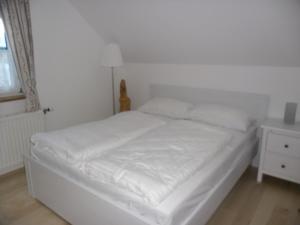 ein weißes Bett in einem Zimmer mit Fenster in der Unterkunft Familienappartement Ötscherbär in Lackenhof