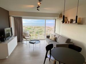 un soggiorno con un divano e un tavolo di Cabien Zeedijk Oostduinkerke a Oostduinkerke