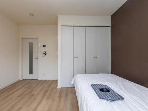 1 dormitorio con cama blanca y armario en Tabist Motodai Business Hotel Kanonji en Kanonji