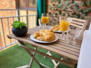 twee borden croissants en glazen sinaasappelsap op een houten tafel bij Apartamento espacioso de diseño a 3 min RENFE. in Córdoba