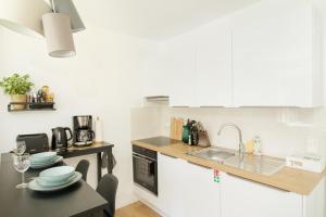 a kitchen with white cabinets and a sink and a table at Löwe Apartment Gold Tiengen Altstadt in Waldshut-Tiengen
