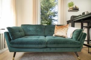 a green couch in a living room with a window at Löwe Apartment Gold Tiengen Altstadt in Waldshut-Tiengen