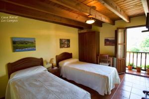 a bedroom with two beds and a balcony at Casa Rural Los campos in Corao