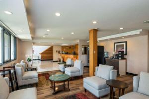 a living room with chairs and tables and a kitchen at Prestige Riverside Lodge Quesnel in Quesnel
