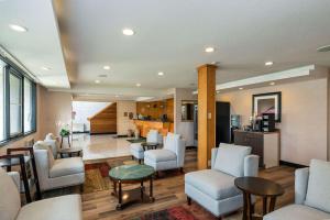 a living room with chairs and tables and a kitchen at Quality Inn in Quesnel