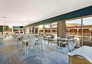 a restaurant with tables and chairs and windows at Merimbula Sapphire Motel in Merimbula