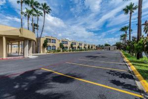una strada vuota con palme ed edifici di Clarion Inn near McAllen Airport a McAllen