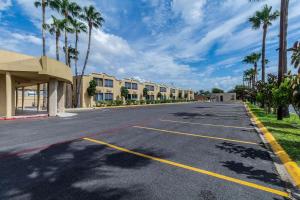 an empty street with palm trees and buildings at Clarion Inn near McAllen Airport in McAllen