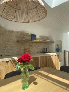 a vase with a red rose sitting on a table at Chambre d'hôtes Hôte des Portes Île de Ré in Les Portes