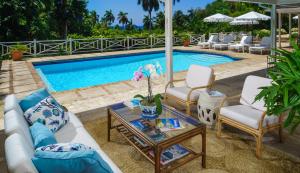 una piscina con sedie a sdraio, tavolo e piscina di Round Hill Hotel & Villas a Montego Bay