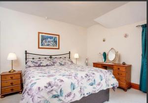 1 dormitorio con cama, tocador y espejo en The Annex Rose Cottage en Lynton