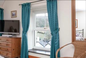 a bedroom with blue curtains and a window at The Annex Rose Cottage in Lynton