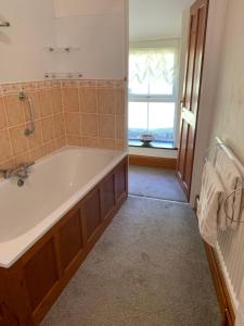 a bathroom with a tub and a window at The Annex Rose Cottage in Lynton +13 photos