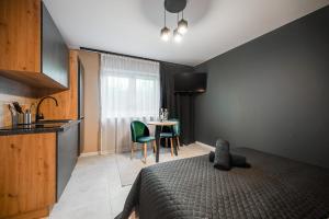 a bedroom with a bed and a kitchen with a table at Loft House Apartment Studio z ogródkiem 1 in Rybnik