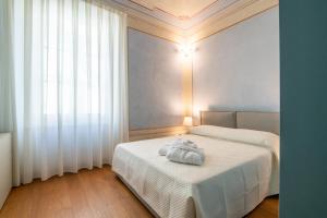 1 dormitorio con 2 camas con sábanas blancas y ventana en La Suite del Borghetto, en Pisa