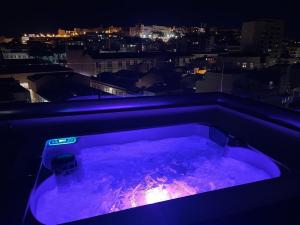 a purple tub with a view of a city at night at 18 Dante Luxury Suites in Cagliari