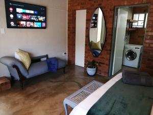 a living room with a couch and a tv at Wild Olive Cottage in Hartbeespoort in Pretoria