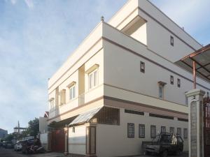 un edificio bianco con un'auto parcheggiata di fronte di OYO 91316 Hh Guest House Makassar a Makassar