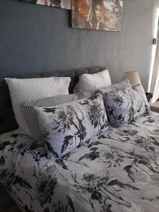 Ariah's Guesthouse and Self Catering في شرق لندن: سرير بملاءات ووسائد سوداء وبيضاء