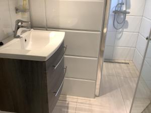 La salle de bains blanche est pourvue d'un lavabo et d'une douche. dans l'établissement 2 persoons appartement de luxe, à Nijverdal