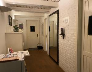 un couloir avec un miroir et un mur en briques blanches dans l'établissement Heddahgaarden, à Bredal
