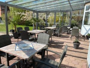 eine Außenterrasse mit Tischen und Stühlen sowie einen Wintergarten in der Unterkunft Hotel Seemeile in Cuxhaven