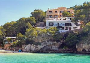 a house on top of a cliff next to the water at Apartamentos Drac in Cala Santanyi