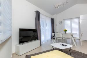 a white living room with a tv and a table at Villa Pinia Fazana in Fažana
