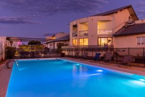 a swimming pool in front of a house at The Originals City, Hôtel Les Dômes, Perpignan Sud Saleilles in Perpignan