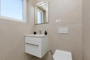 a white bathroom with a sink and a mirror at Villa Pinia Fazana in Fažana +4 photos