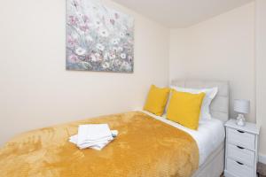 een slaapkamer met een bed met gele kussens en een schilderij bij Modern Studio Apartments in Castle St in Southampton