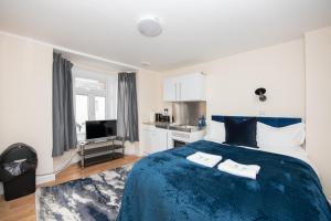a bedroom with a blue bed and a kitchen at Modern Studio Apartments in Castle St in Southampton