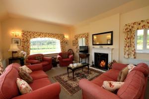 a living room with red couches and a fireplace at Bruntlands Steading in Fochabers