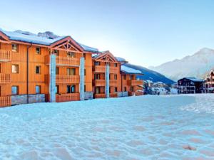 a snow covered parking lot in front of a hotel at Appartement cosy 6 personnes proche des pistes à Val Cenis avec balcon, WiFi et parking sous-sol - FR-1-508-214 in Lanslevillard