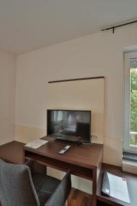 a living room with a desk with a television and a chair at Hotel am Marktplatz in Gangkofen