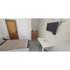 a room with two beds and a table and a tv at Budget Apartman LeLo Centar 3 in Osijek
