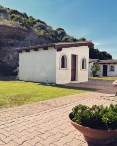 een klein wit gebouw in een tuin met een plant bij Trasicca B&B in Talavà