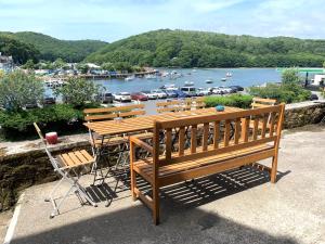 a wooden bench and table with a view of a harbor at Superb House in Looe, Near Beach and Bars with Great Views and free access to a nearby Indoor Swimming Pool in Looe