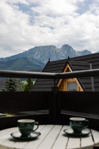 2 tazas en una mesa en un balcón con montañas en Apartamenty Butorowy Zakopane, en Zakopane